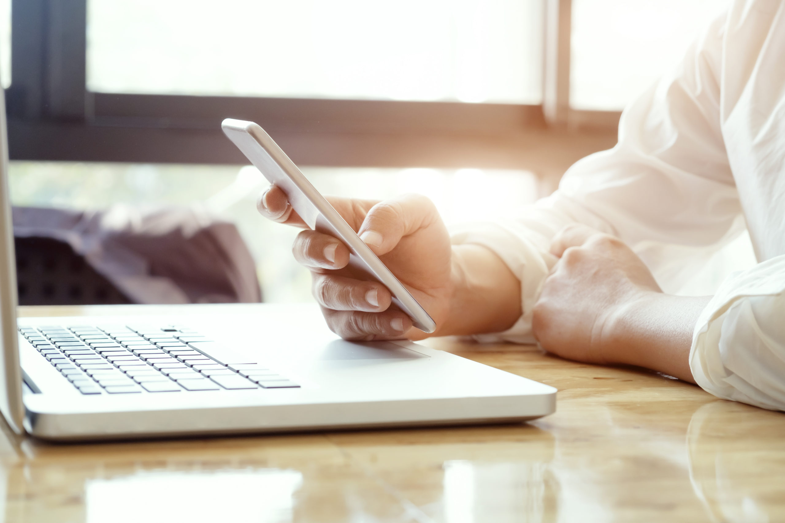 Businessman using laptop and mobile phone for online communication.